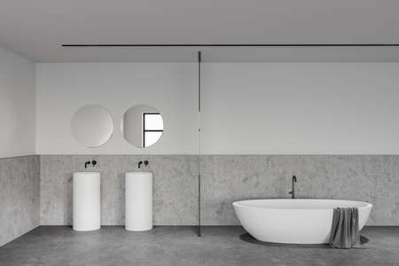 Interior of loft bathroom with white and stone walls, concrete floor, comfortable bathtub and double sink with two round mirrors. 3d renderingの写真素材