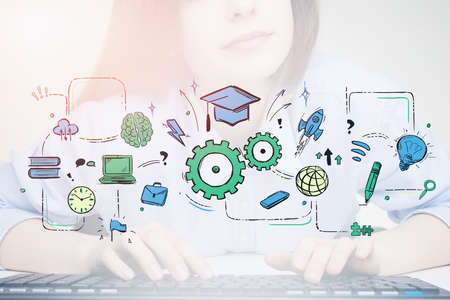 Unrecognizable young woman typing on keyboard at blurry table with double exposure of creative and colorful online education sketch. Concept of e learning and obtaining skills. Toned imageの写真素材