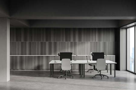 Front view of industrial style open space office with gray and wooden walls, concrete floor and row of white computer tables. Blurry cityscape. 3d renderingの写真素材