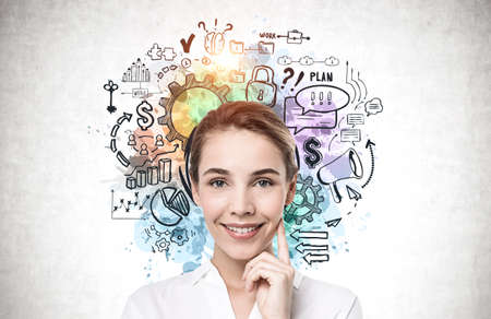 Cheerful young businesswoman standing near concrete wall with creative business plan sketch drawn on...