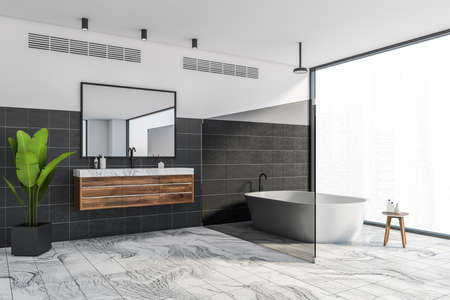 Corner of luxury bathroom with white and black walls, marble floor, comfortable bathtub and double...