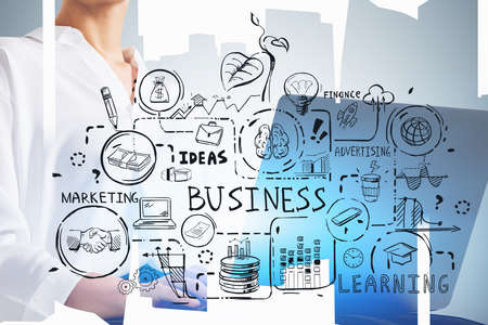 Unrecognizable businesswoman using laptop in blurry abstract city with double exposure of business sketch. Toned imageの写真素材