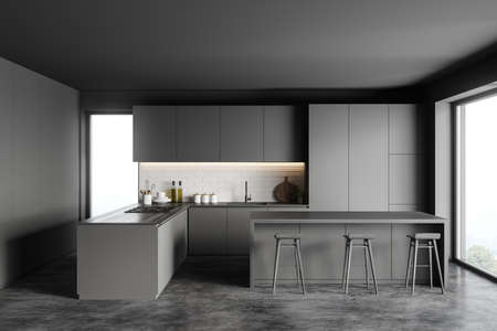 Interior of stylish kitchen with gray and brick walls, concrete floor, gray cupboards and bar with...