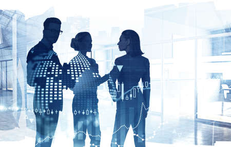 Two businesswomen and businessman working together in blurry office with double exposure of planet hologram. Toned imageの写真素材