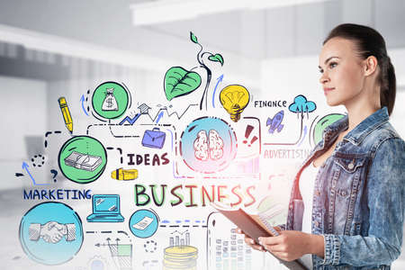 Side view of young businesswoman with notebooks standing in blurry office with double exposure of colorful business sketch. Toned imageの写真素材