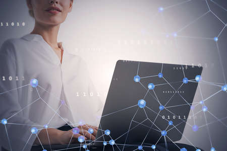 Unrecognizable young businesswoman using laptop over gray background with double exposure of network...