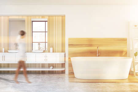 Blurry young woman walking in modern bathroom with white and wooden walls, concrete floor,...