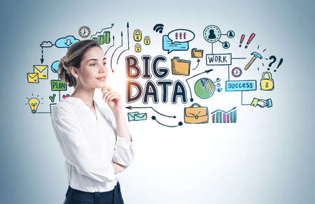 Pensive young European businesswoman standing near gray wall with colorful big data sketchの写真素材