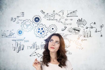 Pensive young businesswoman standing near concrete wall with gears sketch drawn on it.