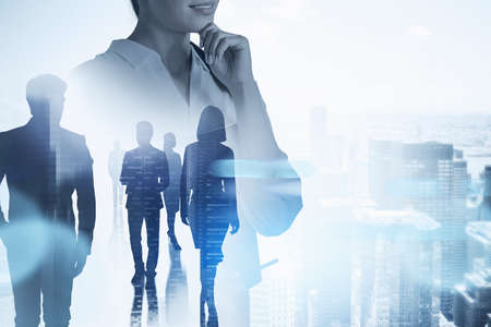 Unrecognizable thoughtful businesswoman working with her team in blurry modern city. Toned image...