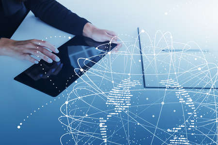 Close up of hands of businessman using tablet in blurry office with double exposure of network...