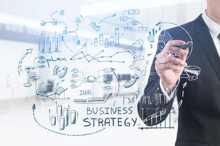 Unrecognizable young businessman drawing business plan sketch in blurry office. Toned image double exposureの写真素材