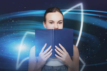 Young businesswoman with book standing over blurry blue background with startup rocket. Toned image