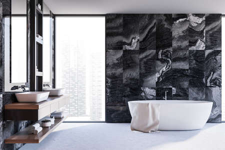 Comfortable double sink with two mirrors and bathtub standing in luxury bathroom with black marble...