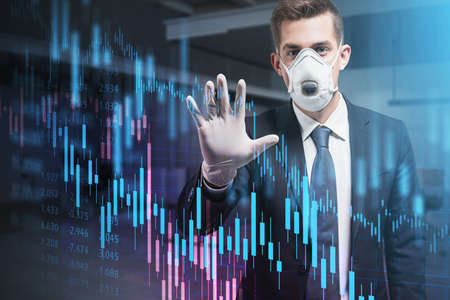 Young businessman in protective mask and gloves working with financial charts over blurry office...