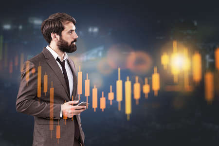 Side view of young bearded businessman using smartphone in blurry dark office with double exposure...