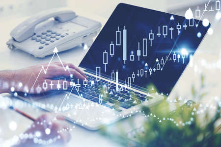 Businesswoman using laptop and taking notes in blurry office with double exposure of financial...