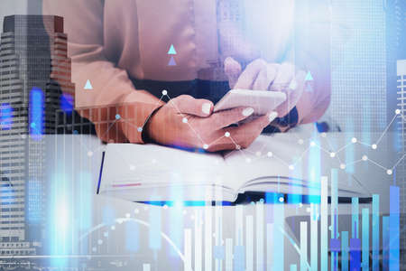 Unrecognizable businesswoman using smartphone in blurry office with double exposure of financial...