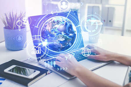 Hands of businesswoman using laptop in blurry office with double exposure of HR interface and planet...