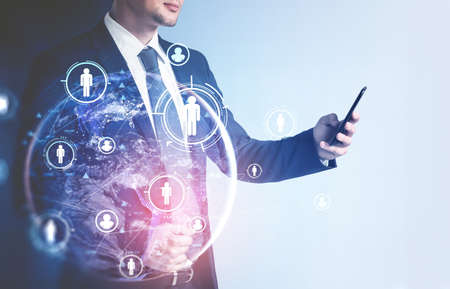 Portrait of unrecognizable young businessman using smartphone with double exposure of HR interface...