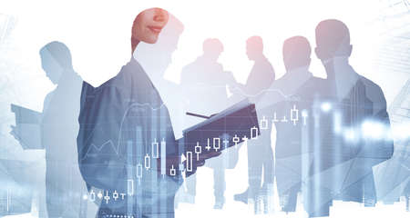 Silhouettes of business people working in blurry city with double exposure of financial graphs....