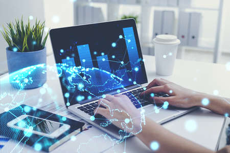 Hands of businesswoman typing on laptop in blurry office with double exposure of immersive network...