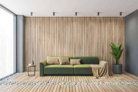 Big wooden living room with sofa and wooden floor, gray wall. Front view of modern green couch with...