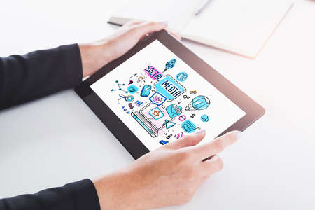 Hands of woman using tablet computer in blurry office with double exposure of social media sketch. Toned imageの写真素材