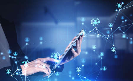 Hands of businesswoman using tablet in blurry office with double exposure of HR interface. Toned...