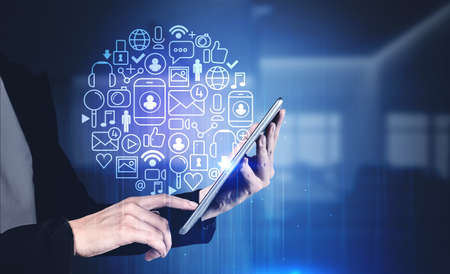 Hand of businesswoman with smartphone in blurry office with double exposure of immersive social media interface. Toned imageの写真素材