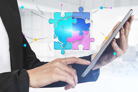 Hand of businesswoman using tablet in blurry office with double exposure of puzzle sketch drawn on...