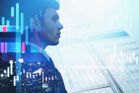 Side view of young businessman standing in blurry city with double exposure of graphs. Toned imageの写真素材