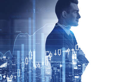 Side view of confident young businessman standing in blurry office with double exposure of graphs....