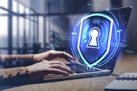 Hands of businesswoman using laptop in blurry office with double exposure of immersive cyber...