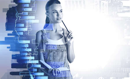 Pensive young woman standing in blurry city with double exposure of graphs. Toned imageの写真素材