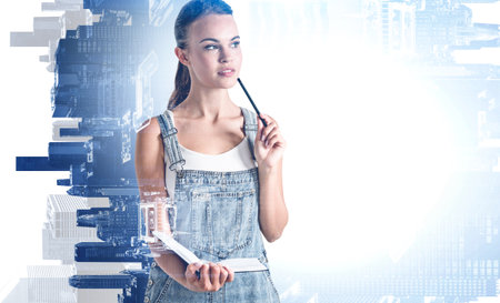 Portrait of pensive young woman holding books in blurry abstract city. Concept of education. Toned image double exposureの写真素材