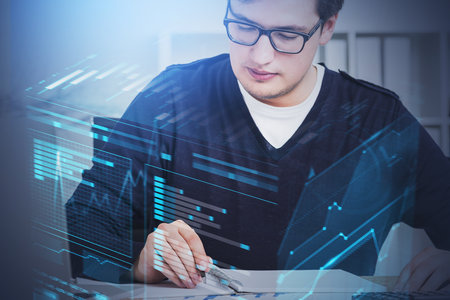 Serious young businessman in glasses working in blurry office with double exposure of graphs. Toned...