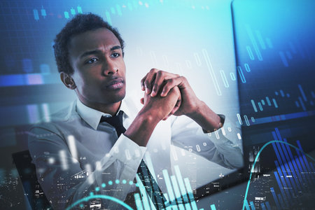 Serious young African American businessman working in blurry office with double exposure of...