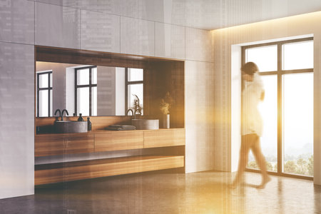 Blurry young woman walking in modern bathroom with white and wooden walls, concrete floor and double sink. Toned image double exposureの写真素材