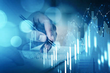 Businessman hand drawing virtual chart or collect stock market rates into notebook to make a...