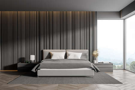 Corner of master bedroom with gray wooden walls, panoramic window with countryside view, comfortable king size bed standing on gray carpet and wood floor. 3d renderingの写真素材