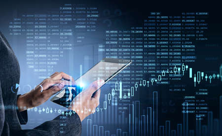 Businesswoman using tablet researching a business report of financial market behavior based on...