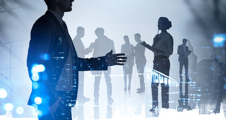 Businessman silhouette in formal suit holds out his hand for a handshake. Corporate culture concept. collegues are on background. Double exposure.の写真素材