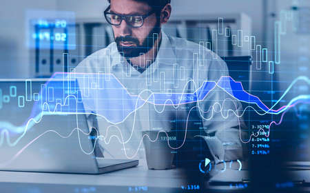 Handsome beard trader in glasses analyzing stock graph chart under the bases of fundamental...