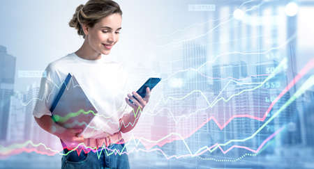 Young smiling woman in casual clothes with phone and notes in hand, double exposure of stock market...