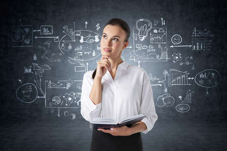 Pensive young businesswoman with planner standing in concrete room with creative business strategy...