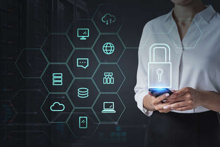 Businesswoman with phone in hands on background of data storage, blue and white glowing icons. Business network symbols. Concept of cyber security and passwordの写真素材