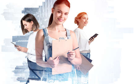 Group of attractive woman students with notebooks, clipboards and smartphones, double exposure. New York cityscape. Concept of corporate communication, teamwork and education.の写真素材