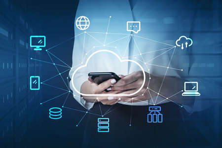 Businesswoman in white shirt holding smartphone in hands, double exposure of cloud service, internet...