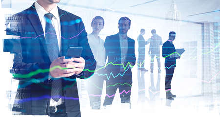 Businessman in formal suit checking stock market rates in smartphone. Hologram charts. Business and...